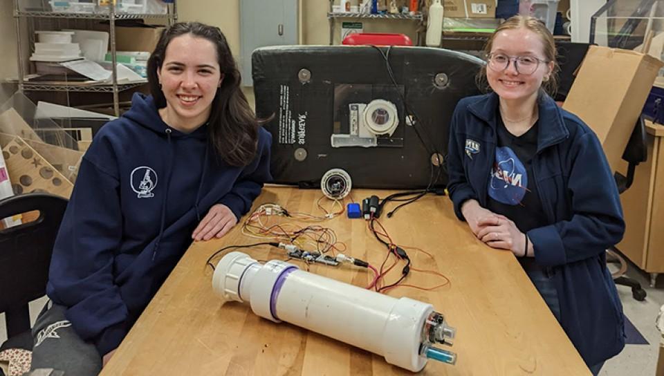 Two U N E students pose with their project in the Makerspace
